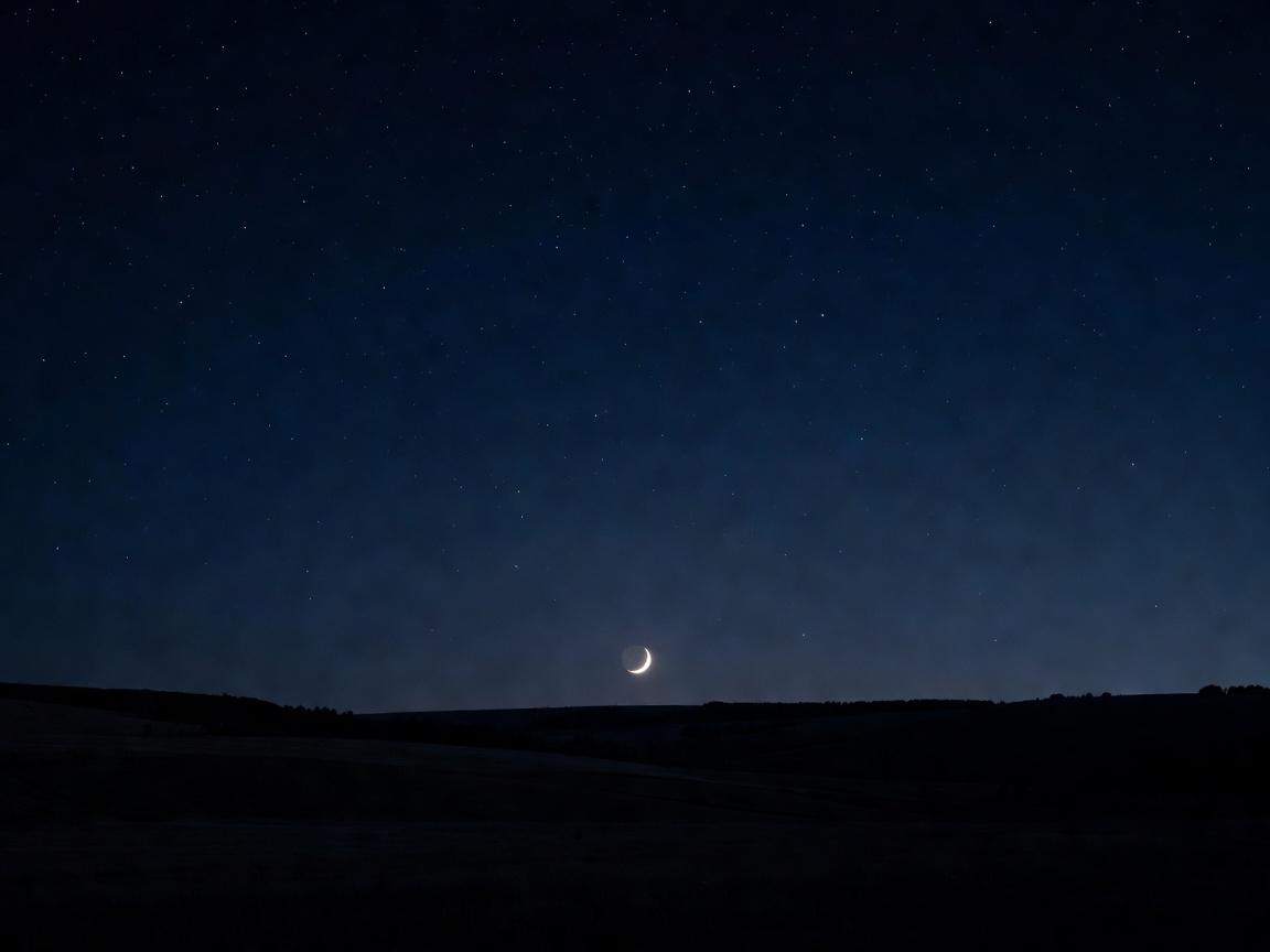 A red-gold crescent moon rising over a dark horizon
